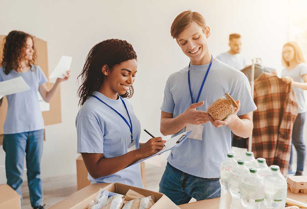 Volunteers organizing donations in a warehouse as part of charitable planning